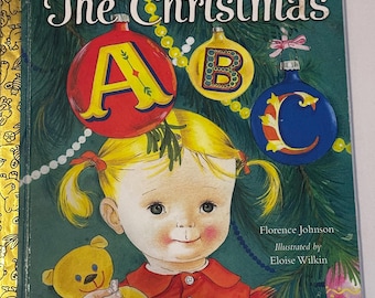 May include: A vintage children's book titled "The Christmas" by Little Golden Book. The cover features a young girl holding a teddy bear, with Christmas ornaments and the letters A, B, and C. The illustration is by Eloise Wilkin.