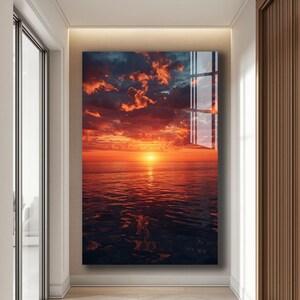 Könnte beinhalten: Ein rechteckiger Wandkunstdruck, der einen Sonnenuntergang über dem Meer zeigt. Der Himmel ist mit orangefarbenen und roten Wolken gefüllt, wobei die Sonne über dem Wasser untergeht. Das Meer spiegelt die Farben des Himmels wider und erzeugt eine lebendige und dramatische Szene.