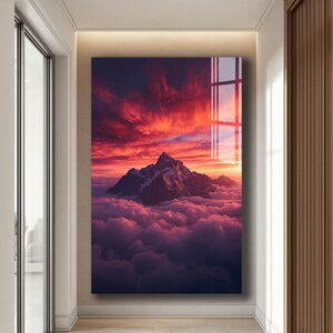 Peut inclure: Impression d'art encadrée d'un paysage de montagne dominant une mer de nuages. Le ciel est embrasé de teintes rouge et orange, créant une scène de coucher de soleil dramatique. L'œuvre est exposée dans un couloir.