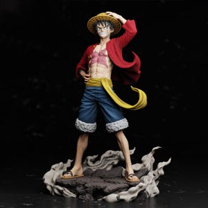 May include: A figurine of a male anime character in a dynamic pose. He wears a red jacket, blue shorts with white trim, and a straw hat. The figure stands on a rocky base with a smoky effect, and has a yellow sash.