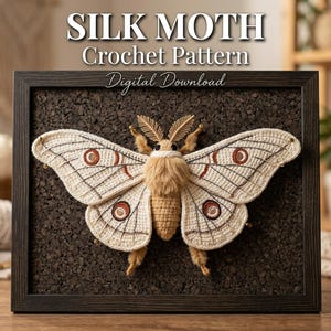 Puede incluir: Una polilla de seda de ganchillo enmarcada, exhibida sobre un fondo oscuro de corcho. La polilla presenta alas de color crema con detalles marrones y patrones circulares. El texto "SILK MOTH Crochet Pattern Digital Download" se muestra en la parte superior.