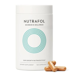 May include: A white cylindrical bottle of Nutrafol Women's Balance hair growth nutraceutical dietary supplement. The bottle has a teal circular design and text. Several brown capsules are scattered in front of the bottle.