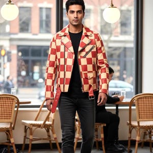 May include: A red and beige checkered leather motorcycle jacket with a notched lapel, silver-tone metal zippers, a front flap pocket, and an adjustable buckled belt at the hem, worn over a plain black t-shirt and dark gray denim jeans.