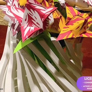 Puede incluir: Un florero blanco impreso en 3D con una estructura de listones en espiral que contiene varias flores de origami. Las flores presentan pétalos de papel con patrones rojos y blancos o amarillos y rojos con hojas de papel verde brillante.