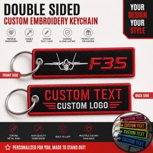 Puede incluir: Llavero bordado personalizado de doble cara con fondo negro y ribete rojo. La parte delantera presenta un gráfico de avión F35 y texto. La parte trasera muestra "CUSTOM TEXT" y "CUSTOM LOGO". Incluye un anillo de metal resistente.