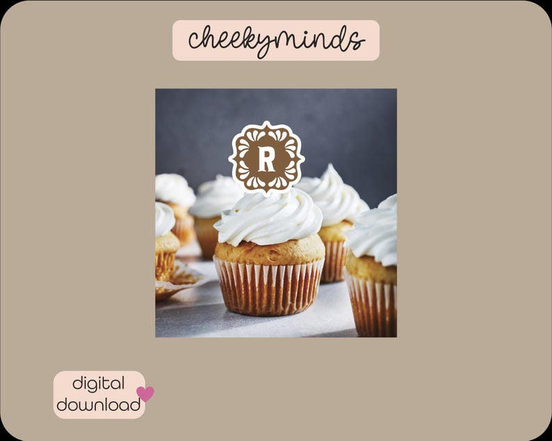 May include: A close-up of cupcakes with white frosting and a brown decorative topper with the letter "R" in the center. The cupcakes are on a gray surface.