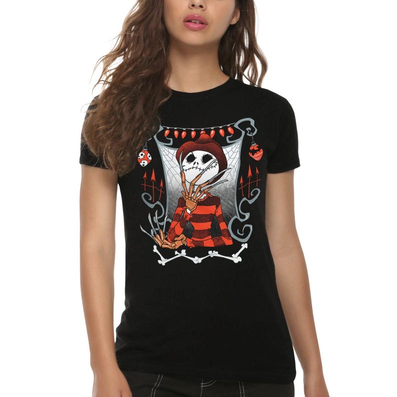 May include: A black short-sleeved t-shirt featuring a graphic print of a skeletal figure wearing a brown fedora and a red and black striped sweater. The figure has long, sharp metal blades on its fingers, surrounded by spiderwebs and red ornaments.