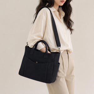 May include: A black tote bag with a shoulder strap and two handles. The bag has two exterior pockets and a snap closure. The bag is made of a sturdy material and is suitable for everyday use.