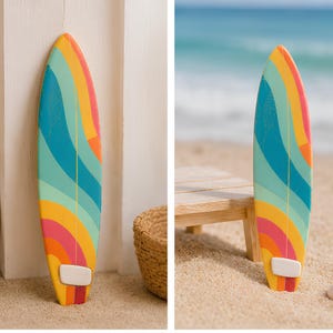 May include: A miniature surfboard featuring a vibrant, multi-coloured pattern of wavy stripes in shades of teal, yellow, orange, and pink. The board has a pointed nose, a rounded tail, and a small white fin attached near the bottom edge.