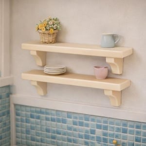 May include: Two cream-colored shelves mounted on a wall, each supported by decorative brackets. The top shelf holds a small basket of flowers and a blue mug. The bottom shelf displays a stack of plates and a pink bowl. The shelves are above a blue tiled surface.
