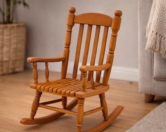 May include: A small, wooden rocking chair with a warm, honey-toned finish. The chair features a slatted seat, curved rockers, and armrests. The back has vertical slats and rounded finials. A classic piece of furniture.