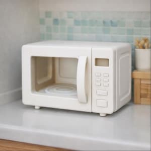 May include: A miniature, cream-coloured microwave oven with a handle and control panel. The interior has a circular design. The microwave sits on a white countertop, with a light blue and white tiled backsplash behind it.