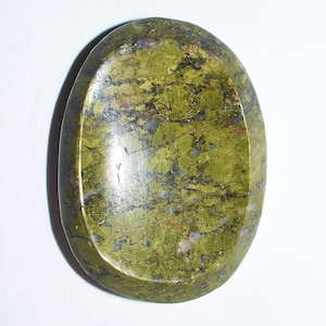 May include: Oval-shaped polished stone with a mix of green, black, and grey hues. The stone has a smooth, glossy surface and a natural, organic appearance. The stone is approximately 7.6 cm long.