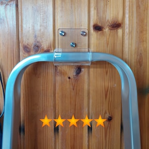 May include: A silver metal shelf bracket with a clear acrylic mounting plate. The bracket is attached to a wooden wall with two screws. Five gold stars are below the bracket.