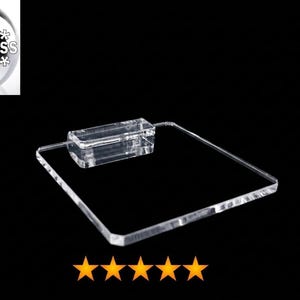 May include: A clear, square acrylic display stand featuring a flat base and a raised rectangular block attachment on one side. The product is branded with the text HiProgress in the upper left corner and five orange stars at the bottom.