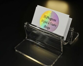 May include: A clear acrylic business card holder containing a stack of white cards. Each card features a circular holographic sticker printed with the black text HiProgress Original & Creative Design. The holder has a tiered, open-front structure.