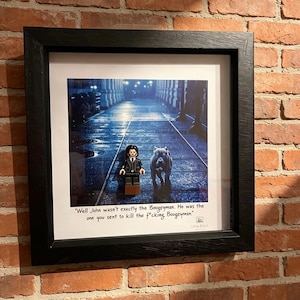 May include: Framed print featuring a Lego figure and a dog walking on a wet street. The image has a dark, cinematic feel with text that reads, "Well John wasn't exactly the Boogeyman. He was the one you sent to kill the f*cking Boogeyman."