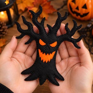May include: A black felt tree ornament featuring a jagged, stitched edge and a spooky face with bright orange felt eyes and a wide, serrated orange mouth. The tree has multiple gnarled, spreading branches and a wide base, crafted from soft fabric.