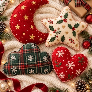 May include: Four felt ornaments in the shapes of a red crescent moon with gold stars, a cream star with holly leaves and berries, a green plaid cloud with white snowflakes, and a red heart with white snowflakes and green sprigs, all with stitched edges.