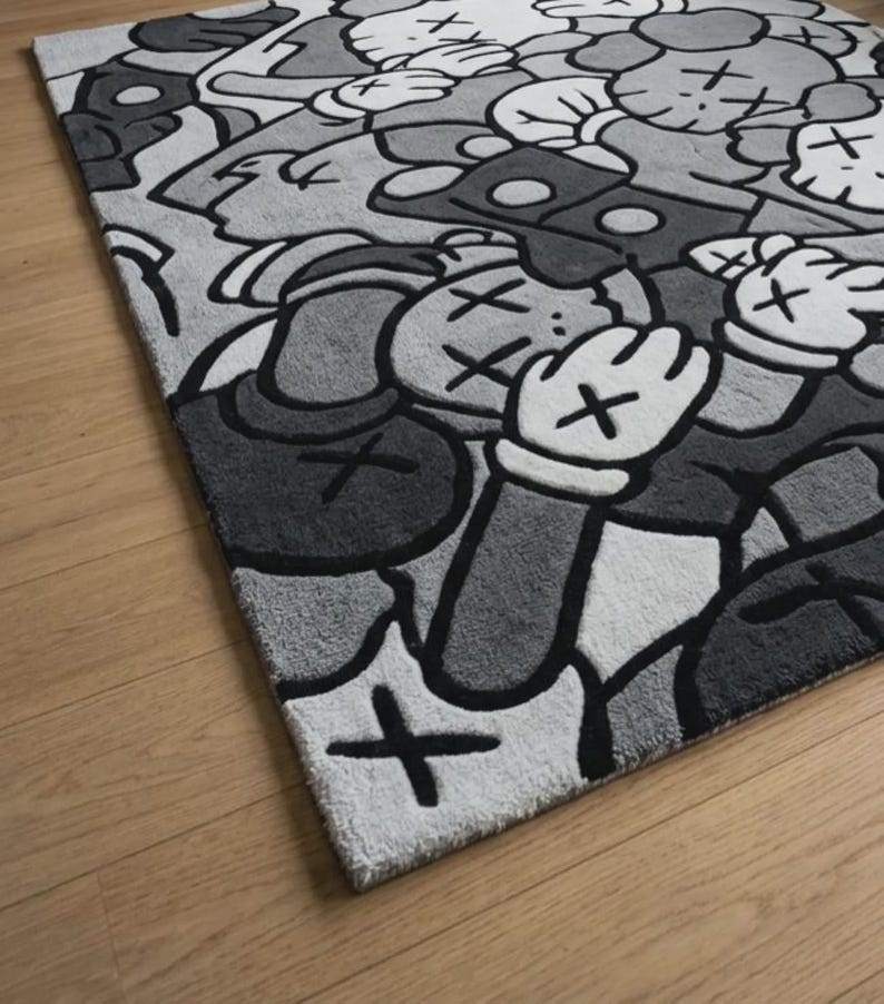 Pu&ograve; includere: Un tappeto rettangolare con un motivo grafico ripetuto in tonalit&agrave; di nero, bianco e grigio. Il design &egrave; composto da figure stilizzate simili a cartoni animati con occhi a forma di X e mani guantate, realizzate in uno stile ad alto contrasto.