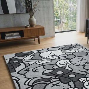 Pu&ograve; includere: Un tappeto rettangolare con un motivo grafico ripetuto nei toni del nero, bianco e grigio. Il design &egrave; composto da figure stilizzate simili a cartoni animati con occhi a forma di X e mani guantate, realizzate in uno stile illustrativo.