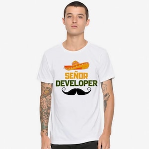 Może przedstawiać: Biała koszulka z sombrero, czarnym wąsem i napisem "Señor Developer" w kolorze zielonym i żółtym. Projekt jest humorystycznym przedstawieniem roli programisty.