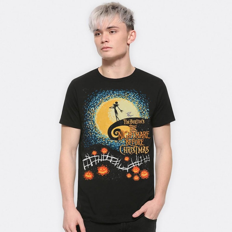 Może przedstawiać: Czarny t-shirt z grafiką z filmu Tima Burtona "Miasteczko Halloween". Projekt zawiera sylwetkę Jacka Skellingtona na wzg&oacute;rzu, pełnię księżyca i tytuł filmu. Pomarańczowe dynie i płot znajdują się na dole.