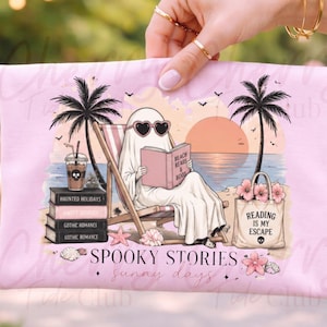 May include: Pink tote bag with a beach scene featuring a ghost reading a book, wearing heart-shaped sunglasses. The text reads "Spooky Stories, sunny days" and "Reading is my escape."
