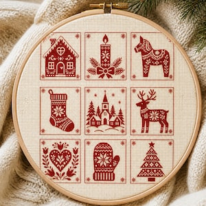 May include: A circular wooden embroidery hoop containing a cream-colored fabric with nine red cross-stitch squares. The designs include a gingerbread house, a candle, a Dala horse, a stocking, a church, a reindeer, a heart, a mitten, and a tree.