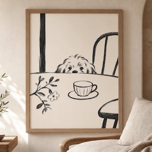 May include: A framed black and white illustration of a dog peeking over a table with a teacup and saucer. The artwork has a minimalist style, with a dog, chair, and floral branch. The frame is a light brown color.