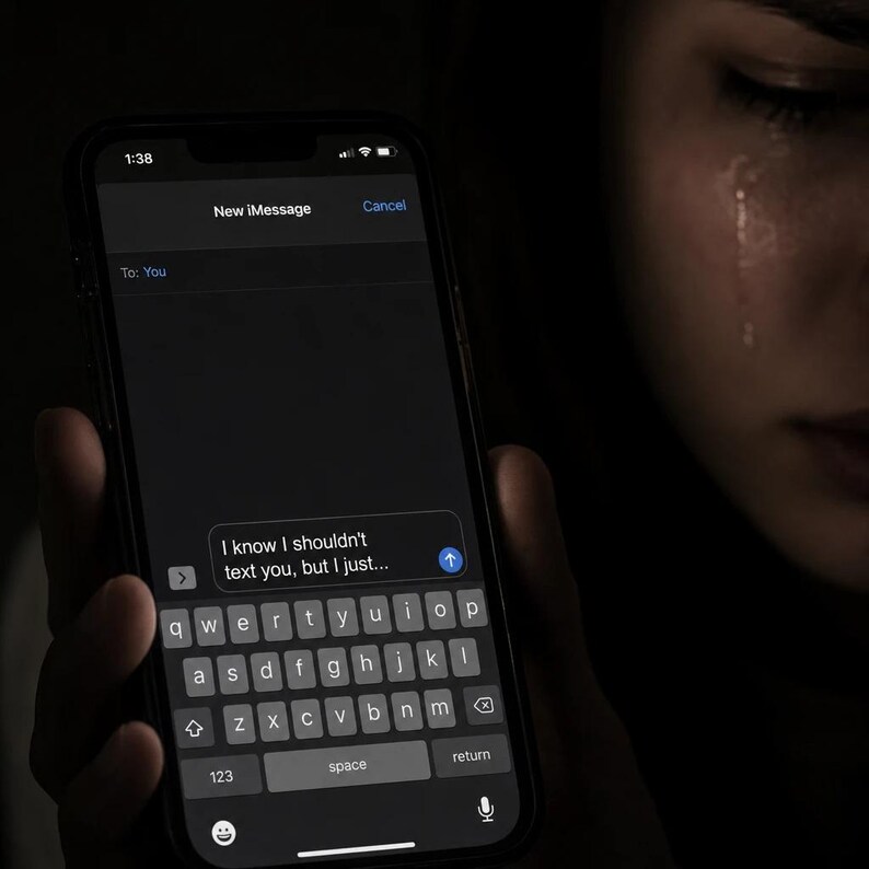 K&ouml;nnte beinhalten: Ein Smartphone-Bildschirm mit einer Textnachricht. Die Sprechblase enth&auml;lt den Text: &bdquo;Ich wei&szlig;, ich sollte dir nicht schreiben, aber ich...&ldquo;. Die Benutzeroberfl&auml;che des Telefons ist dunkel mit wei&szlig;em Text. Die angezeigte Uhrzeit ist 1:38. Das Bild hat eine dunkle, melancholische Stimmung.
