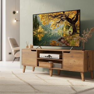 May include: A rectangular wooden media console with two side cabinets and two central open shelves. The unit features light brown wood grain, tapered legs, and recessed handle cutouts. A flat-screen television sits on top displaying a forest landscape.