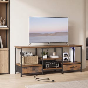 May include: A rectangular media console featuring a dark brown wood-grain top and two matching lower drawers with black metal frames. The unit includes open shelving for storage, housing a woven basket, electronic devices, and gaming accessories.