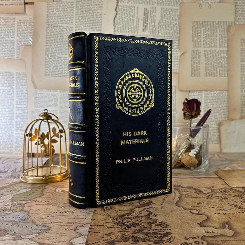 May include: A white ceramic mug with a black handle and the text "But First, Coffee" in a black, handwritten-style font. The mug is on a white surface.