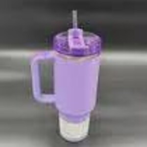 May include: A lavender-colored tumbler with a handle and a straw. The tumbler has a textured lid and a white base. The handle is square and the straw is gray. The tumbler is designed to keep drinks cold.