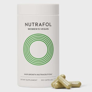 May include: A white cylindrical bottle of Nutrafol Women's Vegan hair growth nutraceutical dietary supplement. The bottle has a green circular design and contains 120 capsules. Three capsules are in front of the bottle.