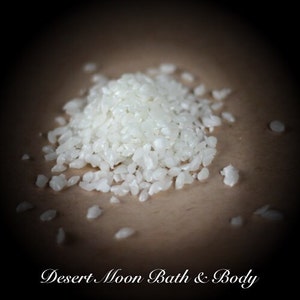 May include: A close-up of a pile of white bath salts on a brown surface. The salts are small and irregular in shape.