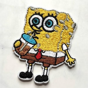Op de afbeelding: Geborduurde patch met een gele cartoonfiguur met grote blauwe ogen en een rode stropdas, die een drankje vasthoudt. De patch heeft een witte rand en is bedoeld om op kleding of accessoires te worden aangebracht.