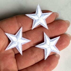 Op de afbeelding: Drie individuele witte, stervormige geborduurde patches. Elke patch heeft een vijfpuntig sterontwerp met een dichte, gestikte textuur en een strakke, witte draadafwerking. De sterren zijn uniform van vorm en grootte en tonen een klassieke vorm.