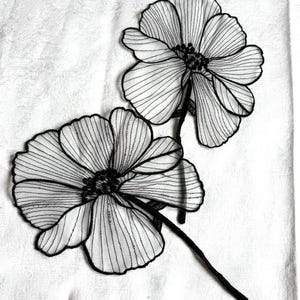 May include: Two black and white floral appliques featuring sheer, translucent petals with fine black embroidered outlines and detailed centers. Each flower is attached to a thin, black stem, creating a delicate, layered botanical design.
