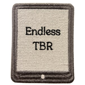 May include: A rectangular embroidered patch featuring a light gray center with a dark gray border. The text "Endless TBR" is stitched in black thread in the center. The design resembles an e-reader device with a small button at the bottom.