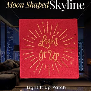 Op de afbeelding: Een vierkante rode geborduurde patch met de gele tekst Light It Up in het midden, omringd door stralende gele lijnen en kleine steraccenten. De patch meet 11,43 cm in breedte en hoogte en heeft een textieloppervlak met textuur.