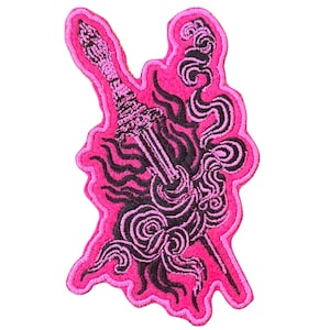 May include: A pink embroidered patch featuring a stylized sword design. The sword is detailed with black accents and surrounded by swirling black lines, set against a bright pink background.