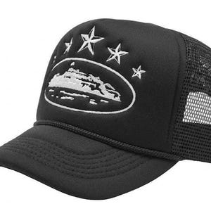 May include: Black trucker cap with a white embroidered mountain and star design. The cap has a curved peak, a mesh back, and an adjustable strap. A fashionable accessory for outdoor pursuits.