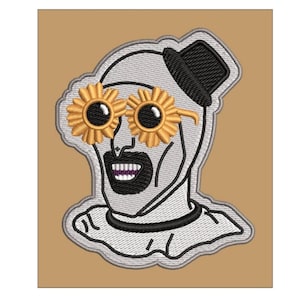 May include: An embroidered patch featuring a white-faced character with a black goatee, wearing a black top hat and yellow flower-shaped sunglasses. The character has a white ruffled collar and is outlined in grey thread against a tan background.