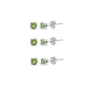 Può includere: Tre paia di orecchini a lobo con pietre preziose rotonde verde chiaro incastonate in metallo color argento. Gli orecchini sono presentati su uno sfondo bianco, evidenziando il loro design semplice ed elegante. Ogni orecchino ha un perno per orecchie forate.