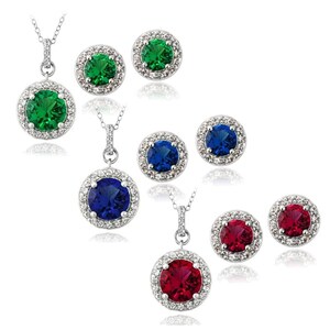 May include: Jewelry set featuring three necklaces and matching stud earrings. Each set includes a round gemstone in green, blue, or red, surrounded by a halo of small, clear stones. The pendants and earrings are silver-toned.