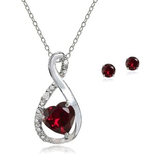 Puede incluir: Un collar plateado con un colgante en forma de corazón de piedra roja oscura y pendientes a juego. El colgante está engastado en un diseño infinito, acentuado con pequeñas piedras transparentes. Los pendientes presentan piedras rojas redondas.