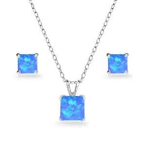 May include: A silver necklace with a square, blue pendant and matching stud earrings. The pendant and earrings feature a vibrant, blue gemstone. The jewelry set is displayed on a white background.