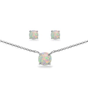 May include: A jewelry set featuring a necklace and matching stud earrings. The necklace has a delicate silver chain with a round, iridescent opal pendant. The earrings also feature round opals. The opals display a range of colors, including white, pink, and green.
